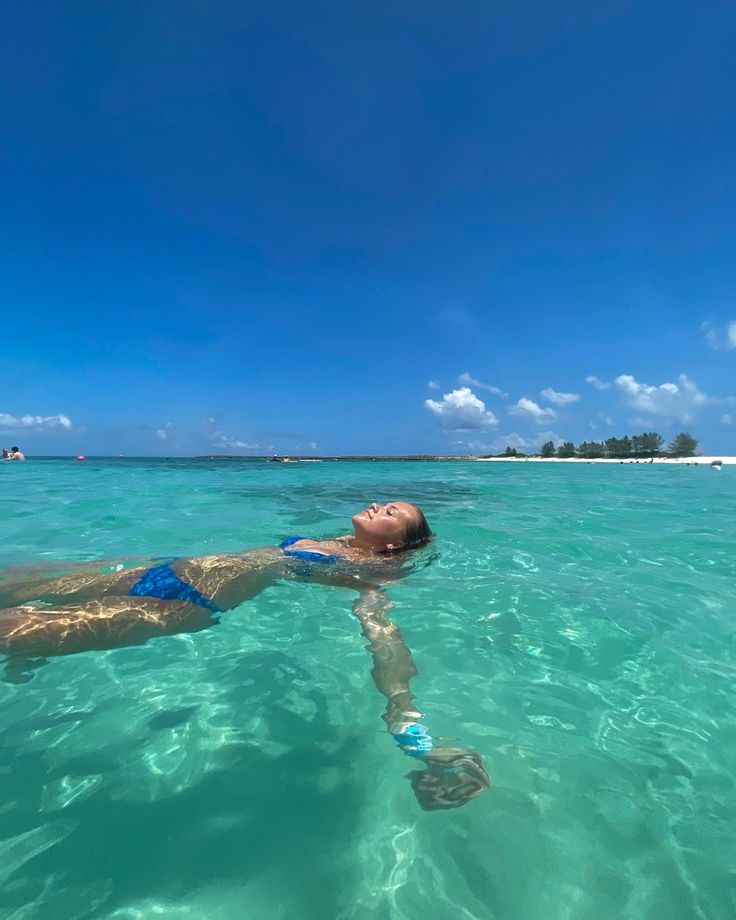 a woman swimming in the ocean with a snorkel on her back and an island in the background