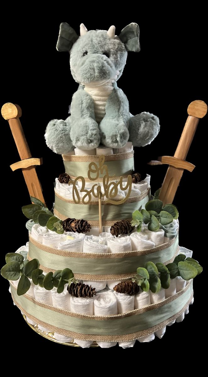 a diaper cake with a teddy bear on top and pine cones in the bottom