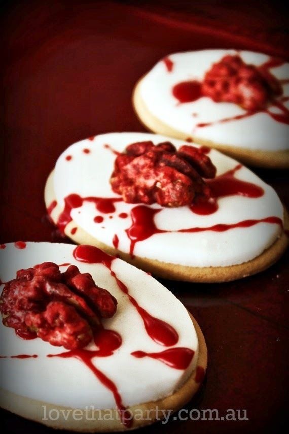 three cookies with white icing and red toppings on them sitting on a table