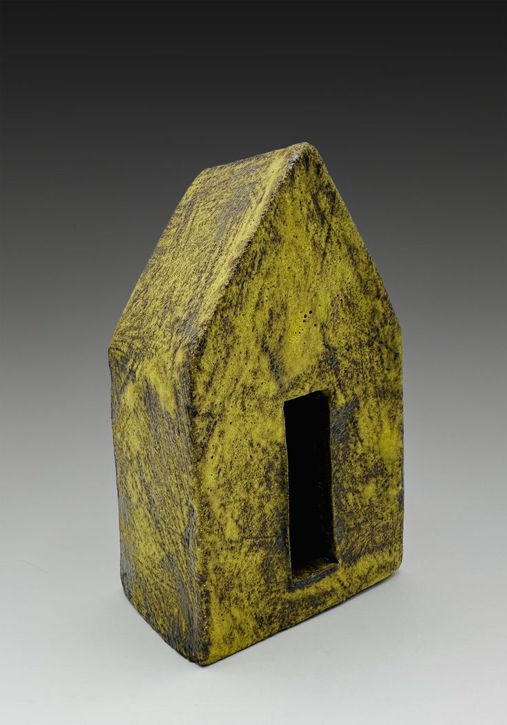 a small yellow house shaped object on a gray background