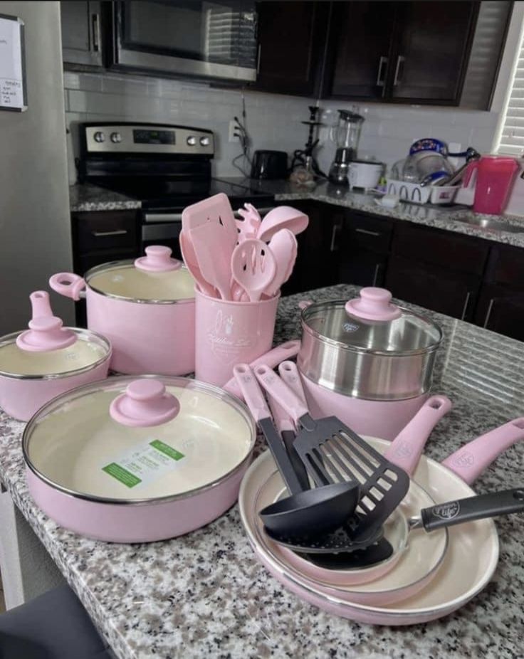 the kitchen counter is covered in pink pots and pans with utensils on them