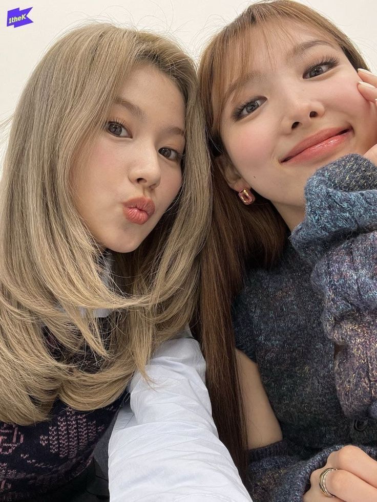 two young women are posing for a photo together, one is holding a teddy bear and the other has her hand on her shoulder