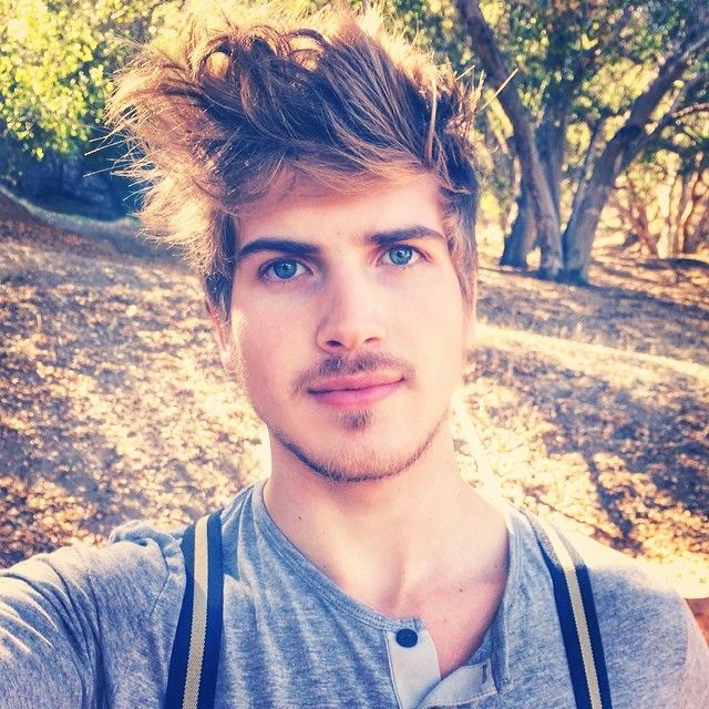 a young man taking a selfie with trees in the background