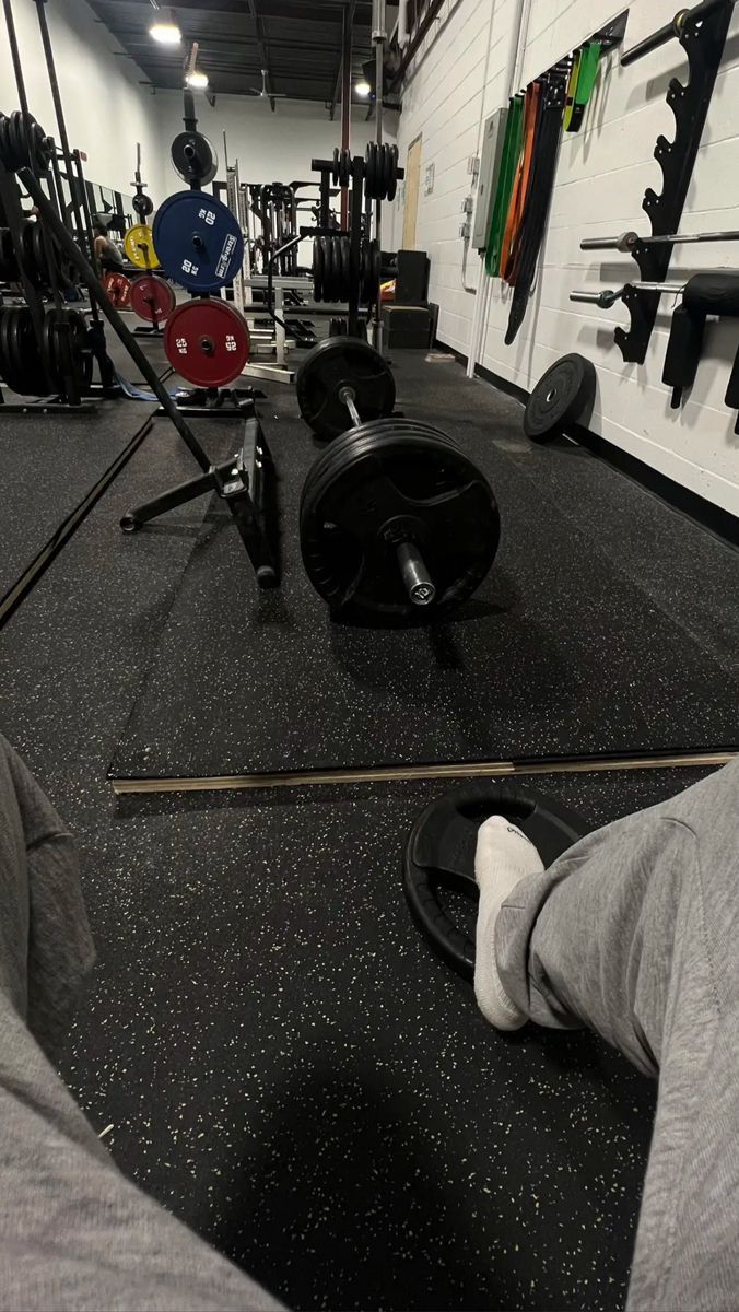 a man is sitting on the ground with his feet up in front of a gym equipment rack