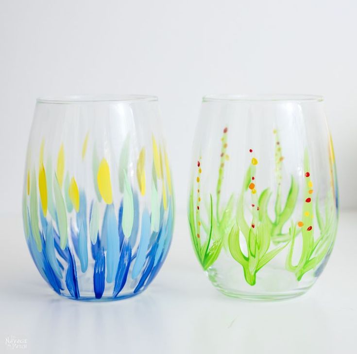 two hand painted glass vases sitting next to each other on a white counter top