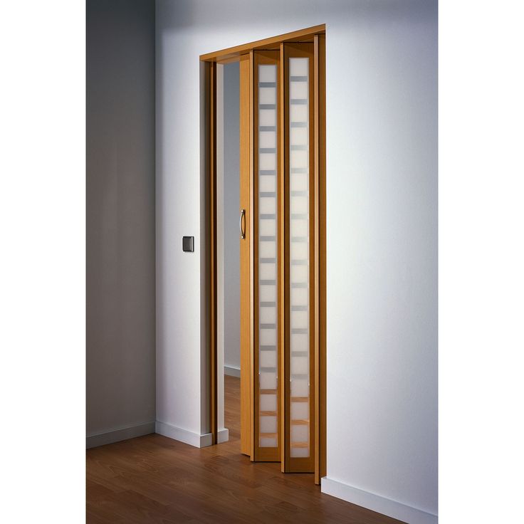 an empty room with a wooden door and glass panels on the doors, in front of a white wall