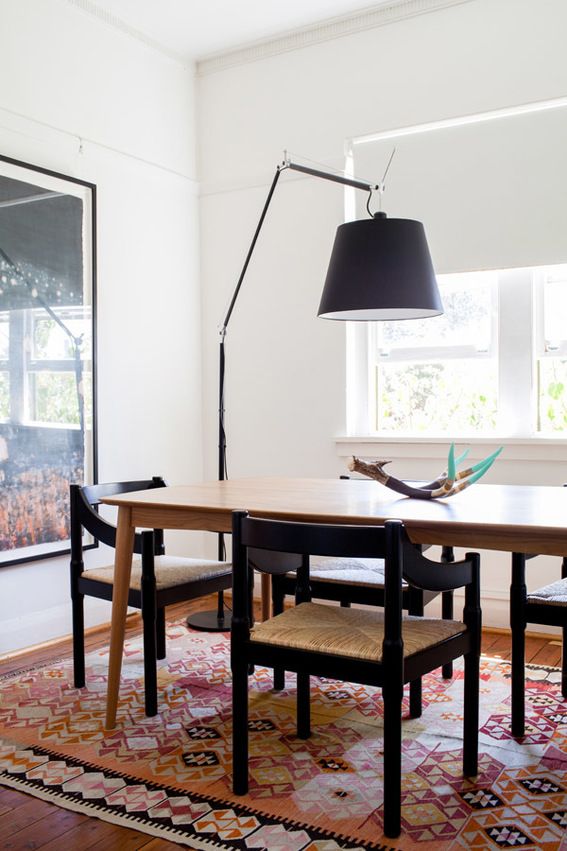 a dining room table with chairs and a rug on the floor in front of it