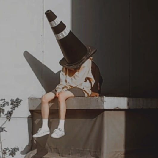 a person sitting on a ledge with a black and white hat over their head,