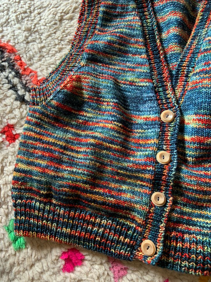 a knitted sweater laying on top of a carpet