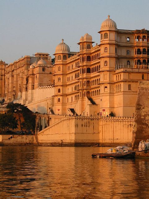 a large building sitting on top of a river next to a boat in the water