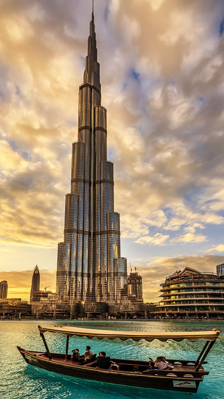 a boat floating on top of a body of water next to a tall building in the background