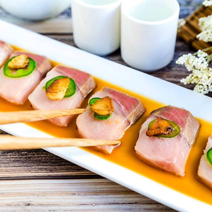 some food is sitting on a plate with chopsticks and sauce in front of it