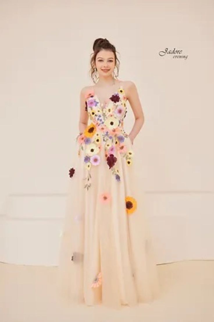 a woman standing in front of a white wall wearing a dress with flowers on it