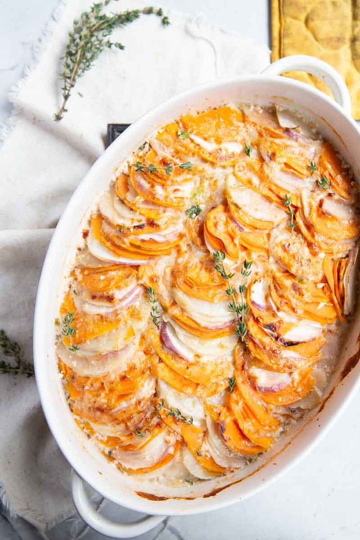 a casserole dish filled with potatoes and onions on top of a white cloth