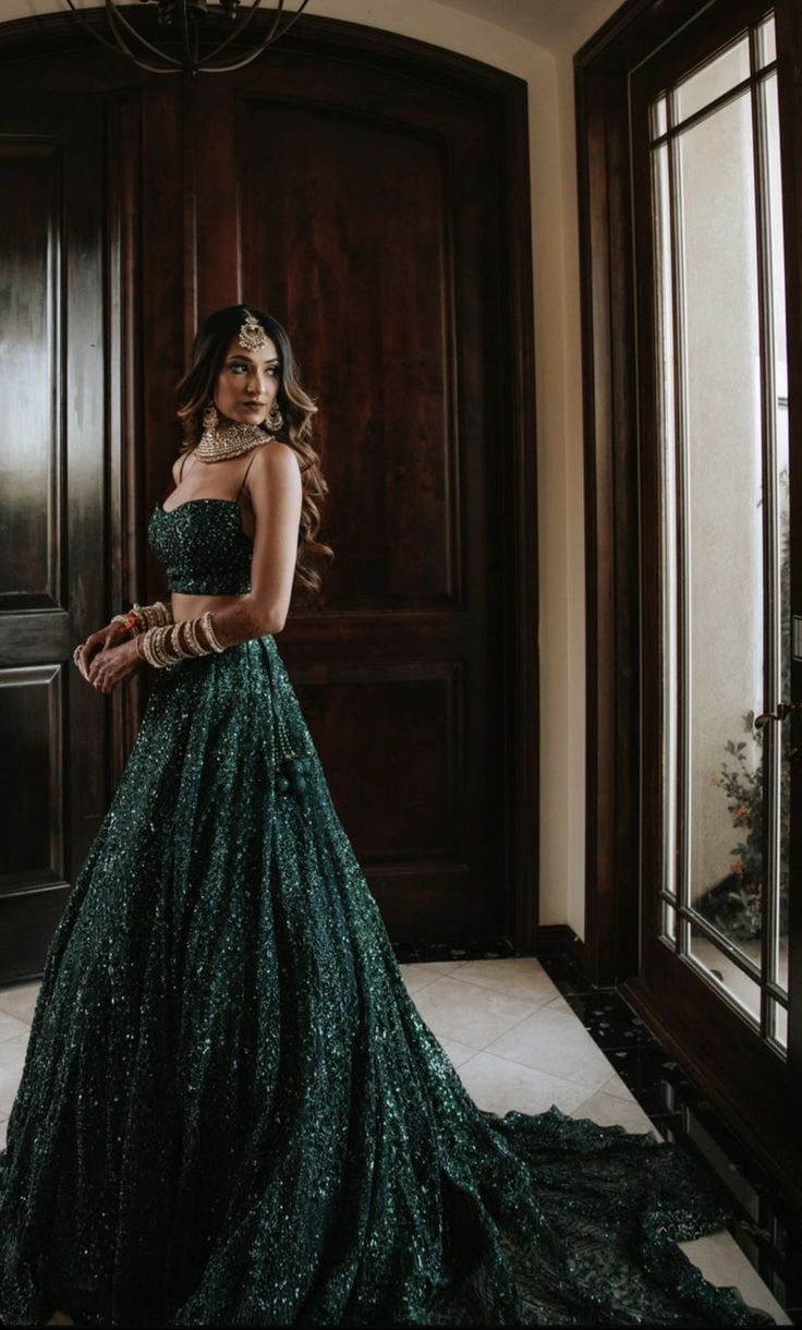 a woman standing in front of a door wearing a green dress with sequins