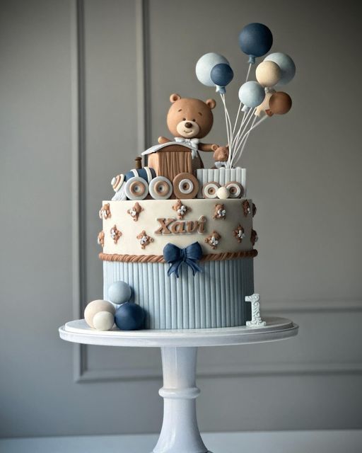 a teddy bear is riding on top of a train cake