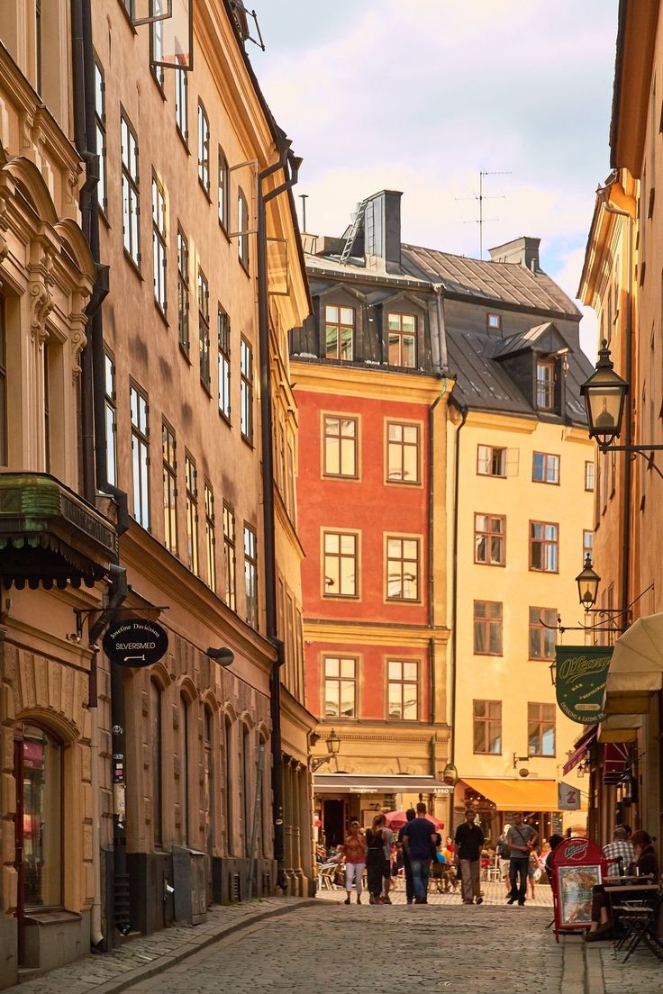 people are walking down an alley way between two buildings with shops on the side and one building has many windows