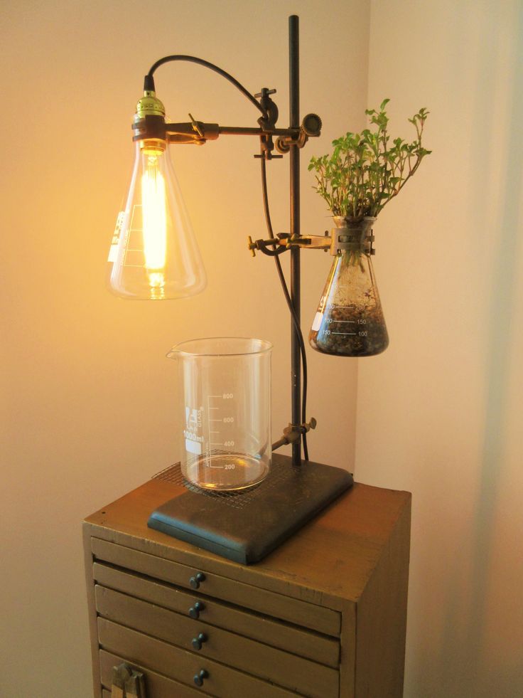 a lamp that is sitting on top of a dresser next to a vase with flowers in it