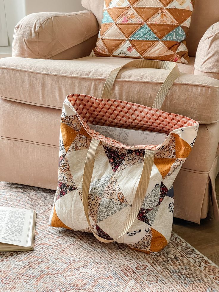 a bag sitting on the floor next to a book and pillow in front of a couch