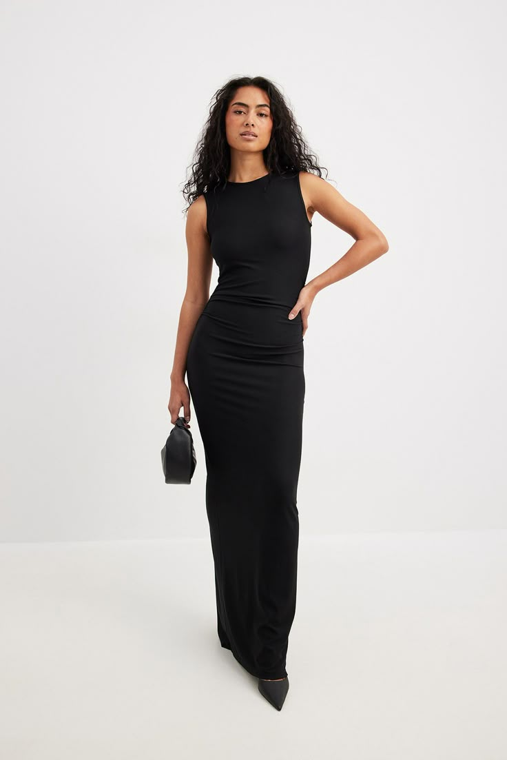 This maxi dress is sleeveless and features a rounded high neckline. It has ruched side seams and a back slit detail. This maxi dress features a stretchy material. Black Dress Sleeveless, America Dress, Maxi Dress Casual, Ruched Maxi Dress, Net Dress, Fitted Maxi Dress, Houndstooth Dress, Crewneck Dress, Maxi Knit Dress