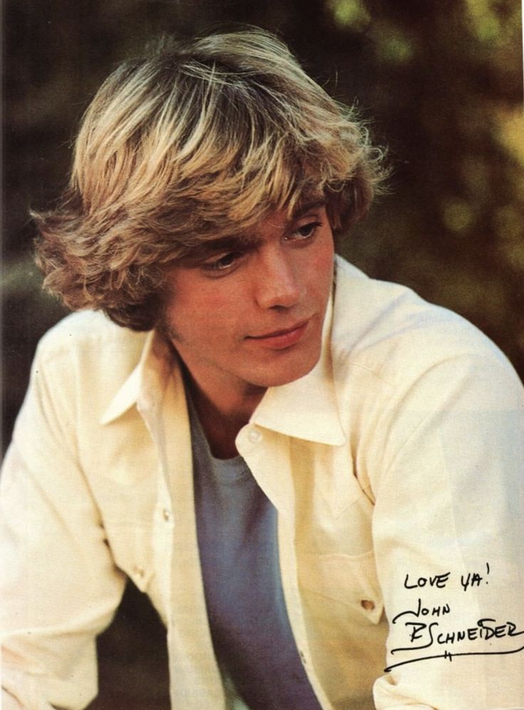 the young man is posing for a photo with his hand on his hip and wearing a white shirt