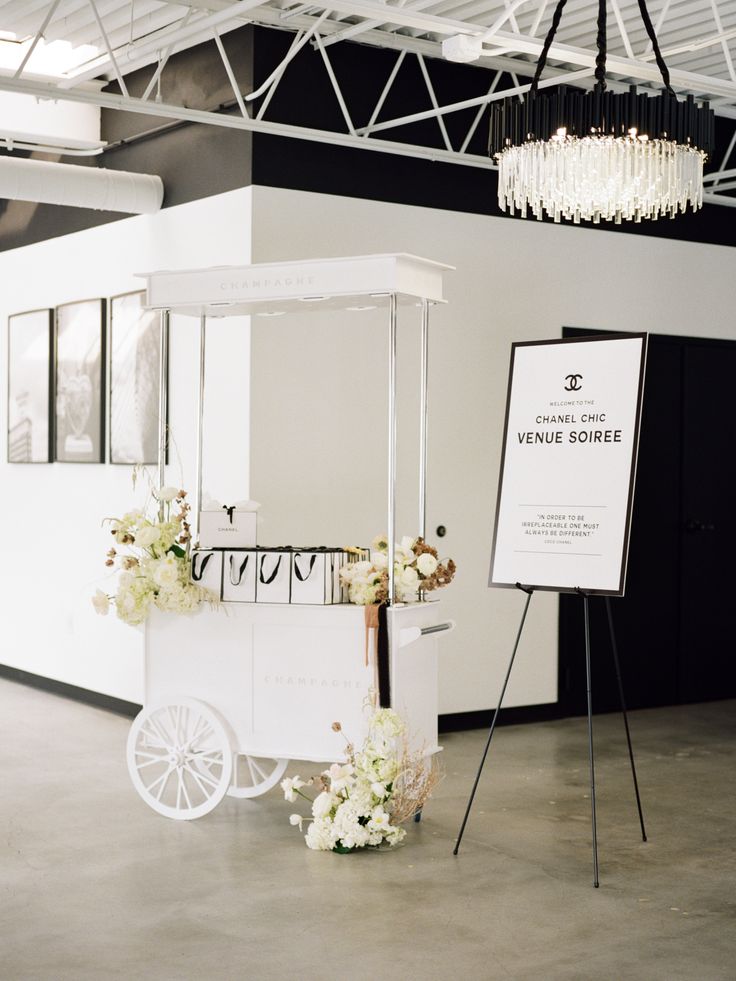 an ice cream cart with flowers on the side and a sign in front of it