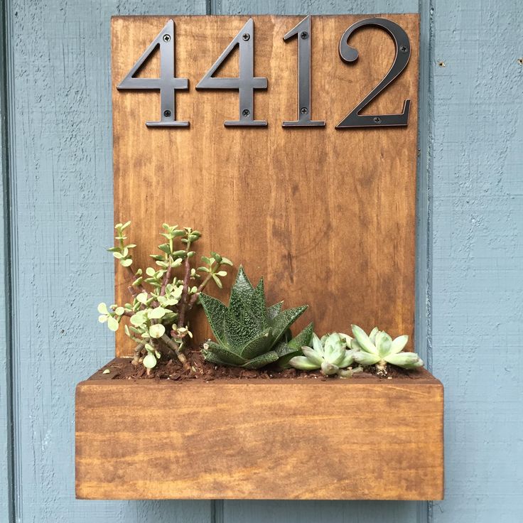 a wooden house number sign with succulents and plants