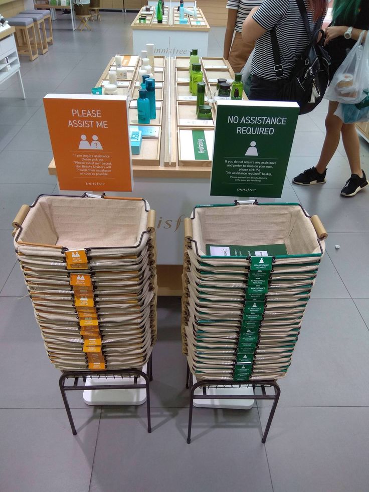 there are many stacks of books on the table with people walking by them in the background