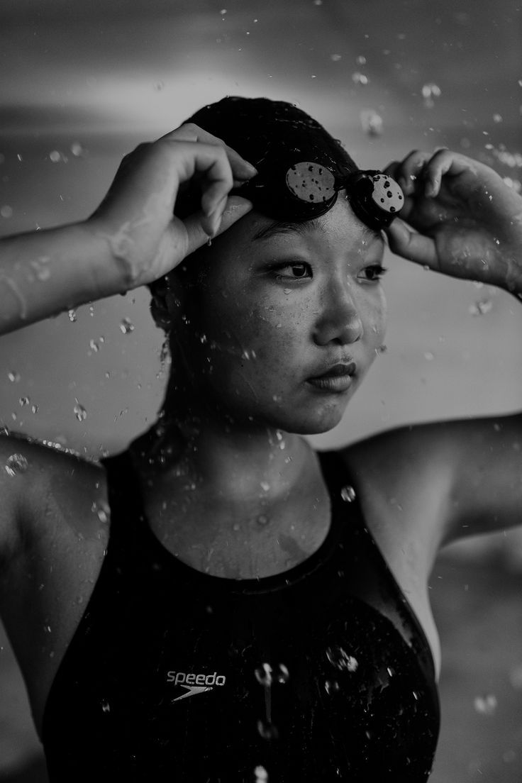 black and white photograph of a woman holding her hair in the air with water droplets surrounding her