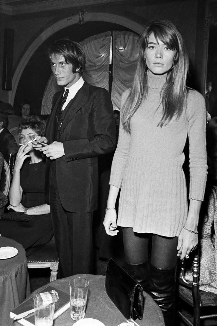 a woman standing next to a man in a suit and tie at a dinner table