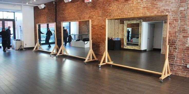 a group of mirrors sitting on top of a wooden floor next to a brick wall