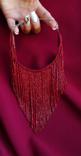 a woman's hand holding a red beaded necklace