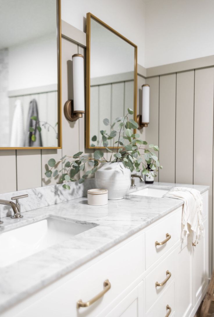 a bathroom with marble counter tops and gold framed mirrors