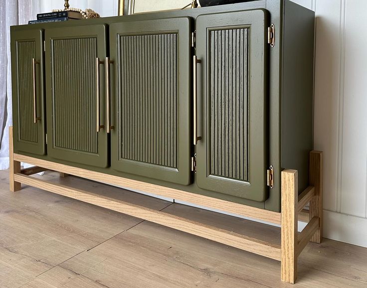 a green cabinet sitting on top of a hard wood floor next to a wall mounted mirror