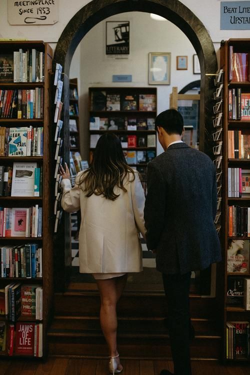 a man and woman are walking down the stairs in front of a book store with bookshelves