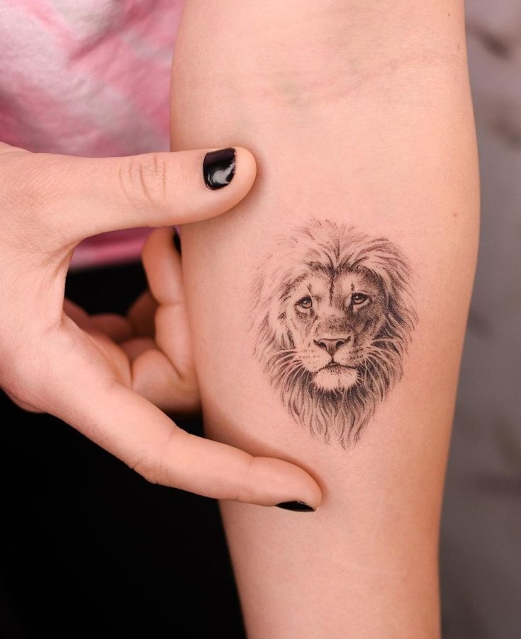 a woman's arm with a small tattoo of a lion on the left side