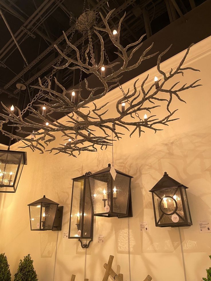 some lights are hanging from the ceiling in a room with white walls and branches on it