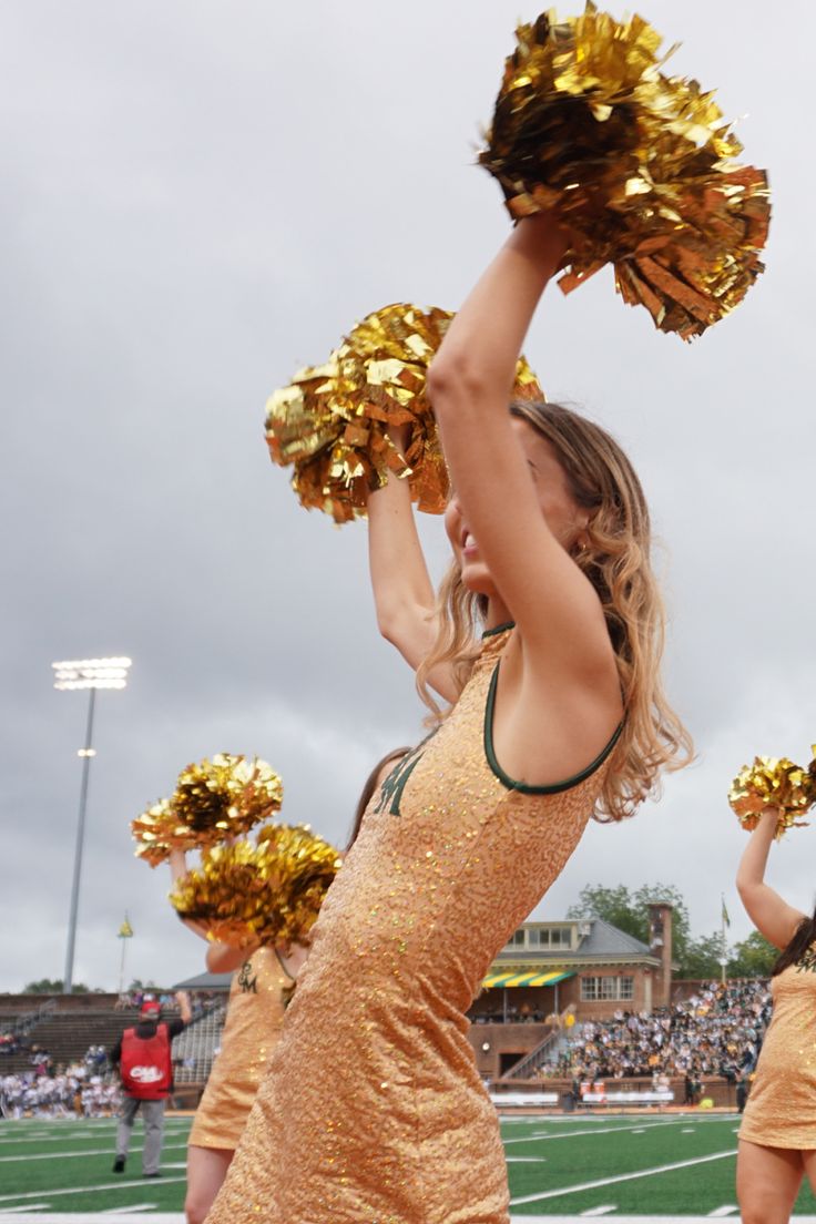 the cheerleaders are wearing gold dresses and holding their pom poms