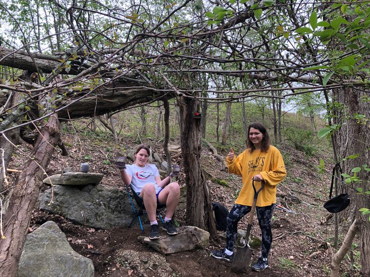 two women sitting on rocks in the woods