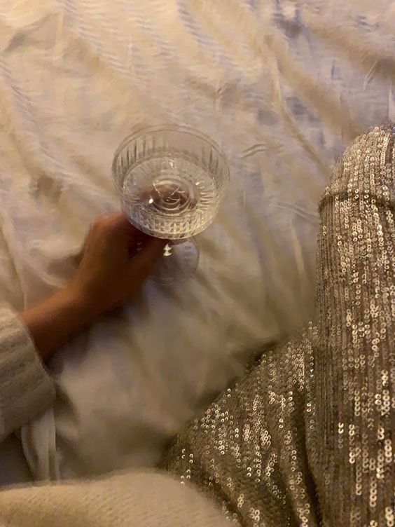 a person laying on a bed holding a glass bowl