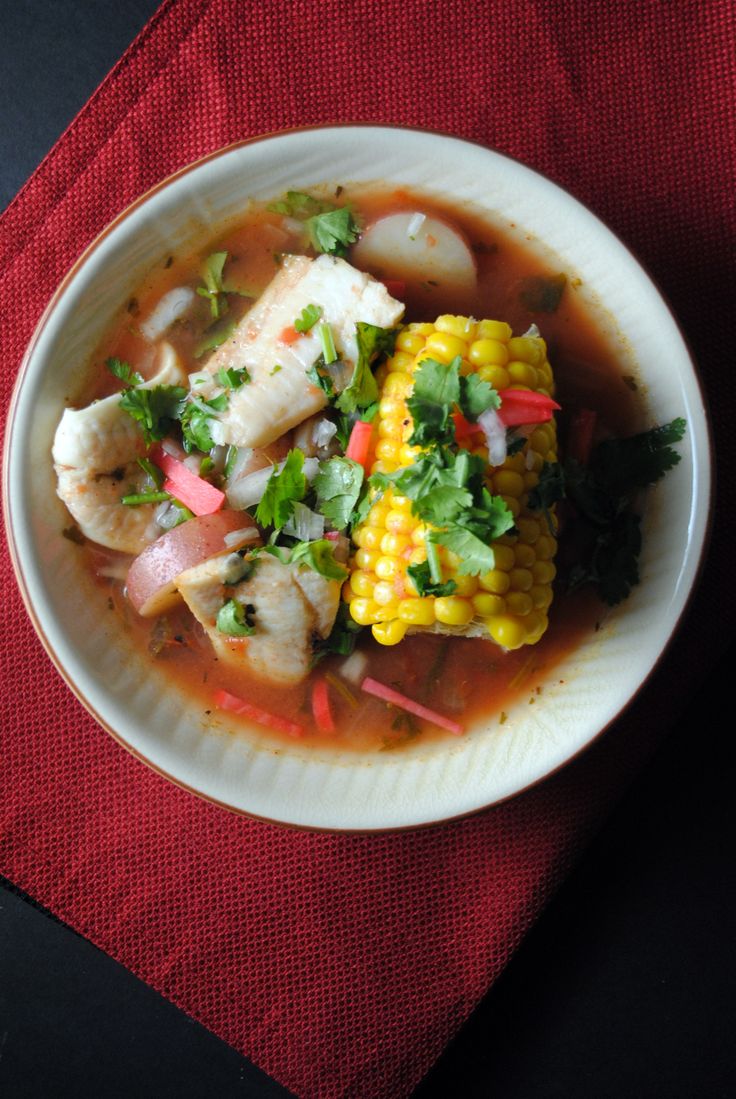 a white bowl filled with food on top of a red table cloth next to a napkin