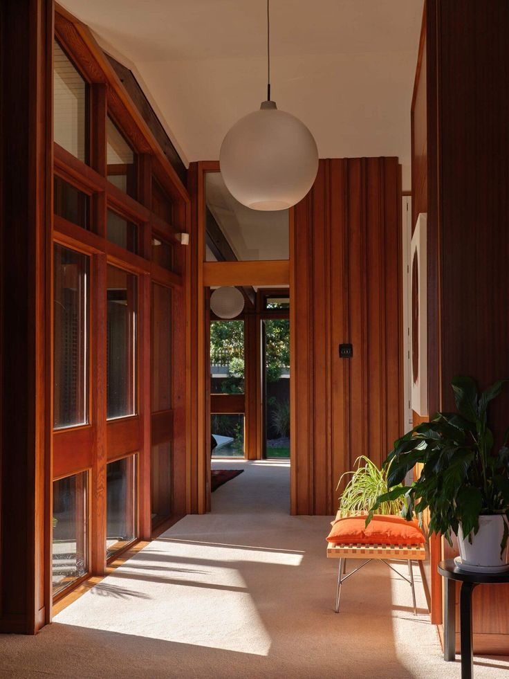 an orange chair sitting in the middle of a hallway next to a plant and door