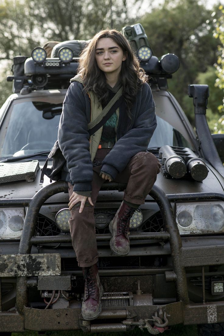 a woman sitting on the hood of a vehicle