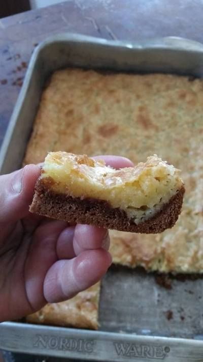 someone is holding up a piece of food in front of a pan full of bread