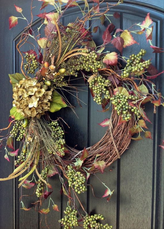 a wreath is hanging on a door with leaves and berries around it, as if for the fall season