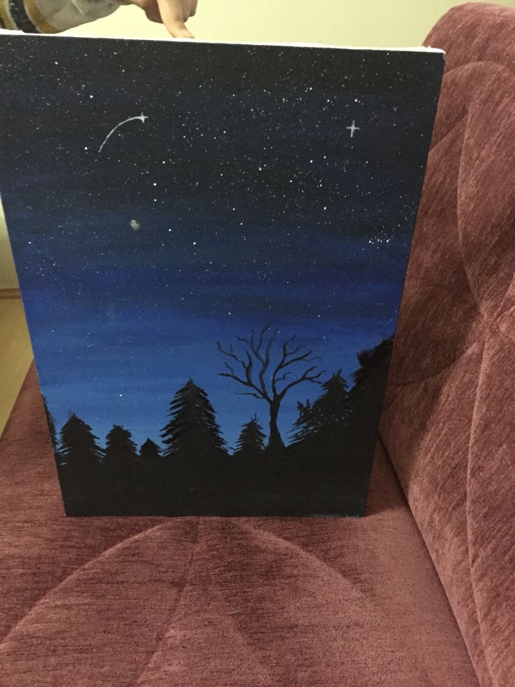 a painting of a night sky with trees and stars in the background on a brown couch