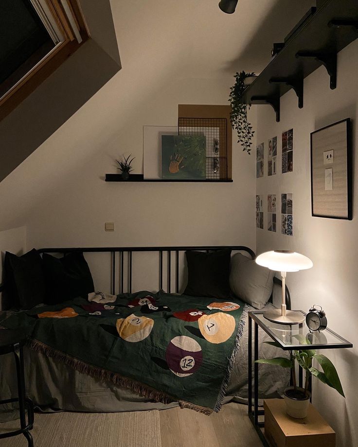 a bed sitting under a window next to a lamp on top of a wooden floor