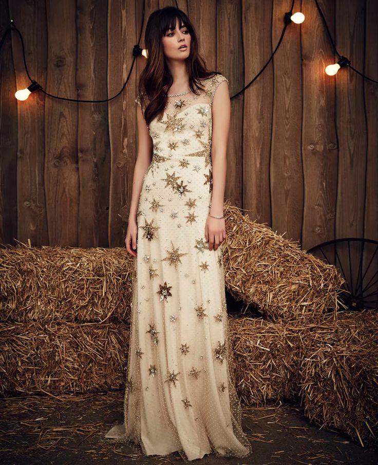 a woman standing in front of hay bales wearing a dress with stars on it