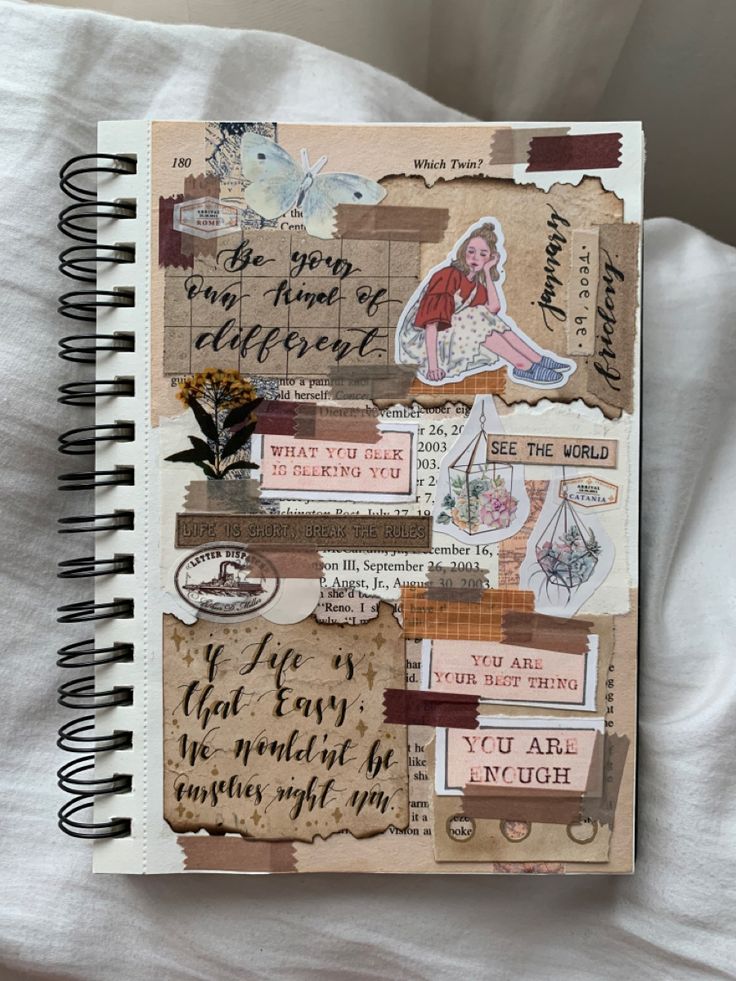 an open notebook with words and stickers on the cover, sitting on top of a bed