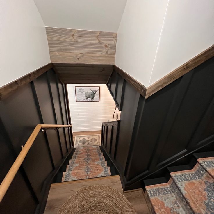 the stairs are made of wood and have black painted panels on them, along with an area rug